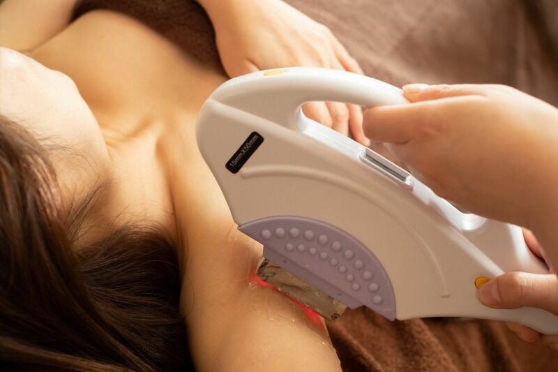 女性の脇の脱毛を進めるスタッフ